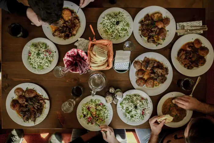 Vue de dessus d'une grande table garnie de plats variés partagés entre amis.